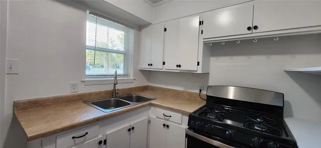 a kitchen with granite countertop a sink stove and cabinets