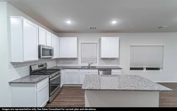 a kitchen with stainless steel appliances granite countertop a sink stove and microwave