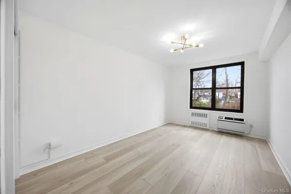 an empty room with windows and chandelier fan
