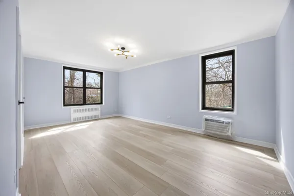 a view of an empty room with a window and wooden floor