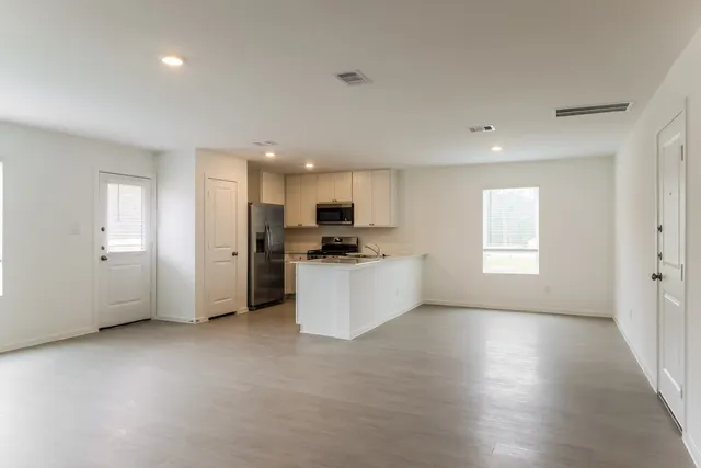 a kitchen with stainless steel appliances a sink a stove a microwave a refrigerator a window