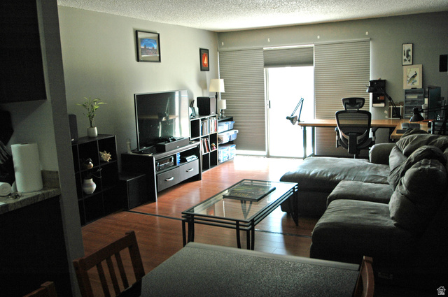 46 Lester Avenue, Unit G 24 Murray, UT 84107 - Photo 10 of 16 Living area featuring wood-finish flooring, light grey wall paint, and a sliding glass door with Cordless Blackout Top Down Bottom Up Cellular Shades