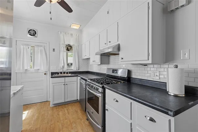 a kitchen with stainless steel appliances granite countertop a sink a stove and a refrigerator