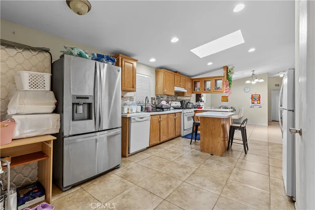 4801 West 1st Street Santa Ana, CA 92703 - Photo 14 of 19 a kitchen with stainless steel appliances granite countertop a refrigerator a sink a stove and white cabinets