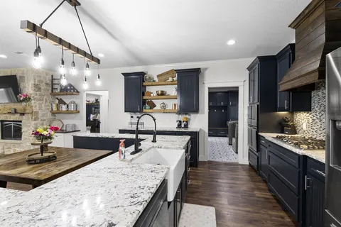 a kitchen with granite countertop kitchen island a sink stove and wooden floor