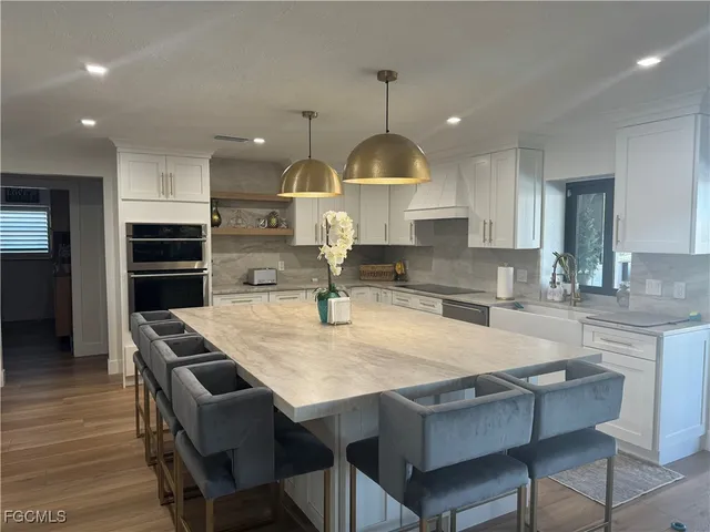 a kitchen with granite countertop a table chairs stainless steel appliances and wooden floor