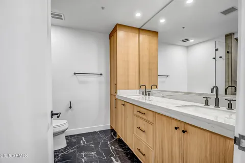 a bathroom with a double vanity sink toilet and a mirror