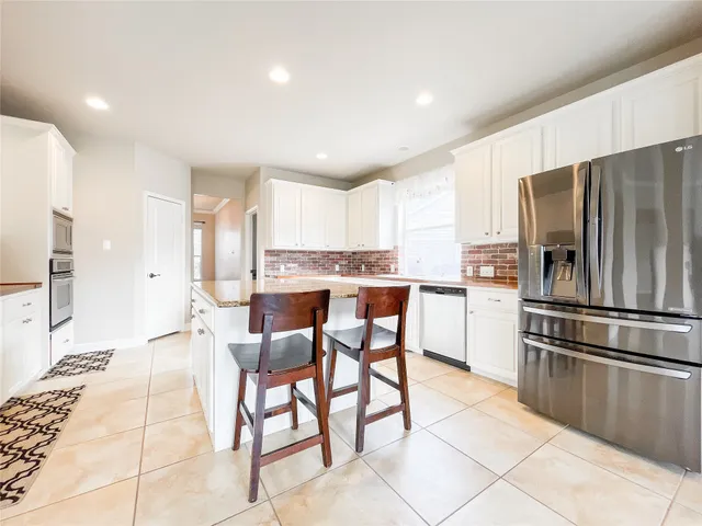 a kitchen with stainless steel appliances granite countertop a refrigerator and a stove top oven