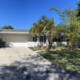 a view of a white house with a yard and palm trees