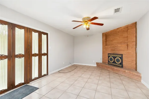 a view of an empty room with window and chandelier fan