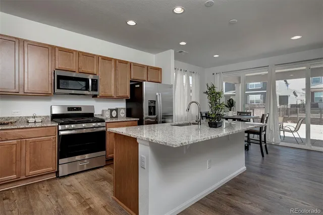 a large kitchen with stainless steel appliances granite countertop a stove a sink a refrigerator a microwave a dining table and chairs