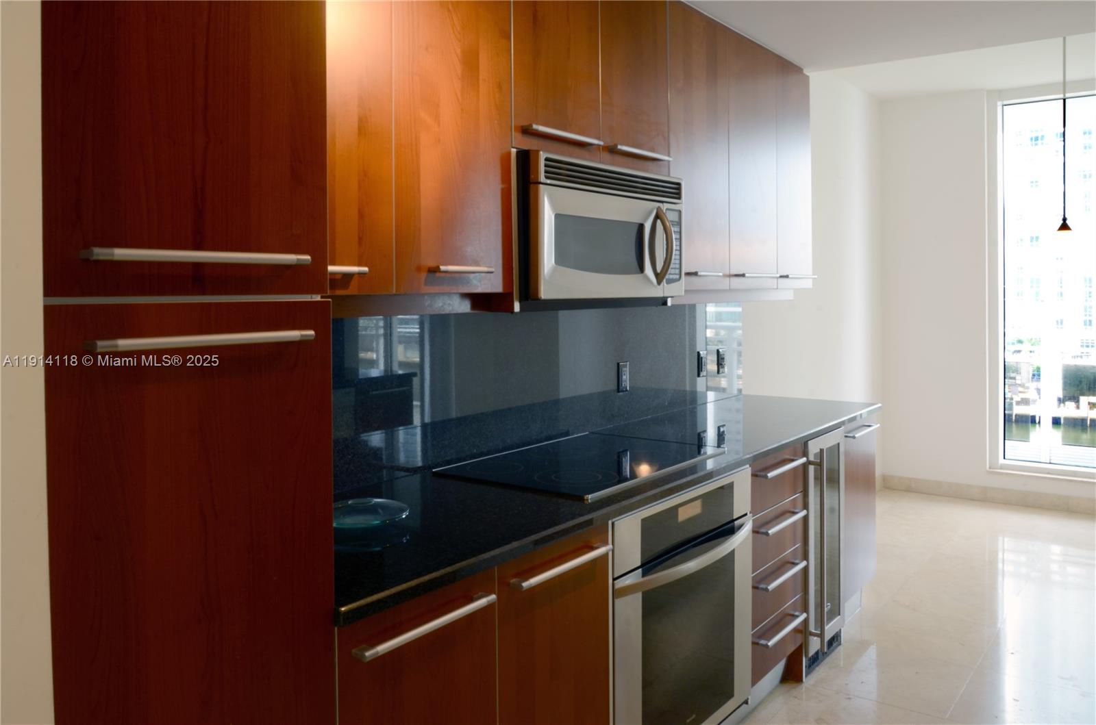 901 Brickell Key Boulevard, Unit 705 Miami, FL 33131 - Photo 16 of 41 a kitchen with granite countertop a stove and a microwave