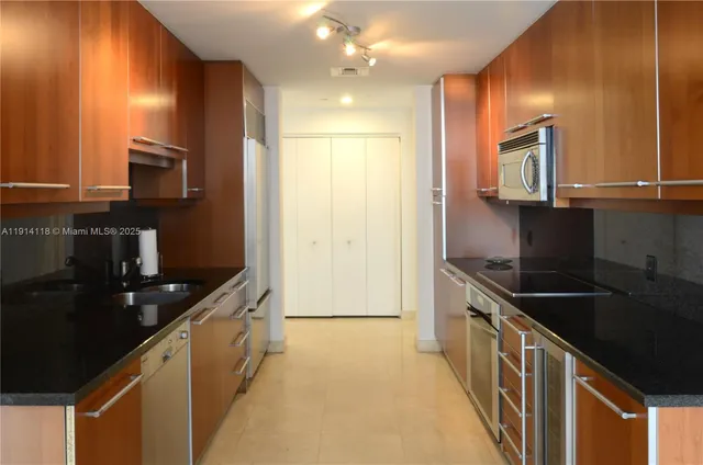 a kitchen with stainless steel appliances granite countertop a sink and a refrigerator