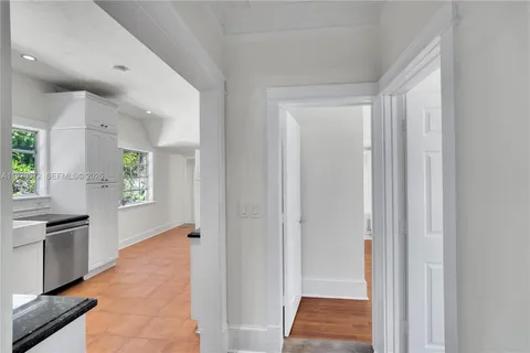 a view of hallway with granite countertop cabinets and black appliances