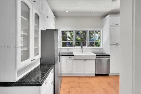 a kitchen with granite countertop a sink stove and refrigerator