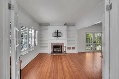a view of a livingroom with wooden floor a fireplace and windows