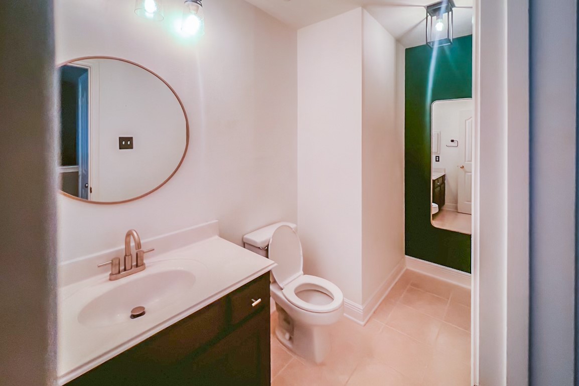 22402 Rue Canyon Court Katy, TX 77450 - Photo 11 of 18 Style meets functionality in this beautifully appointed full bath. It features a dark wood vanity with a crisp white countertop and a contemporary brushed-metal faucet. An elegant round copper-trimmed mirror adds designer flair, while a deep-green accent wall creates a dramatic, high-end backdrop for a full-length dressing mirror.