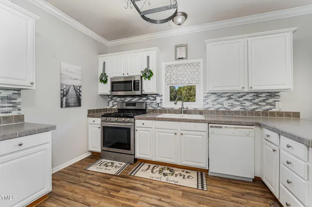 a kitchen with granite countertop a stove a sink and a microwave