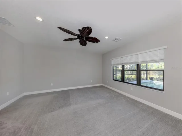 an empty room with windows and ceiling fan