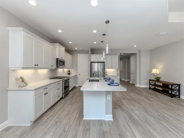 a large kitchen with stainless steel appliances lots of counter space and wooden floor