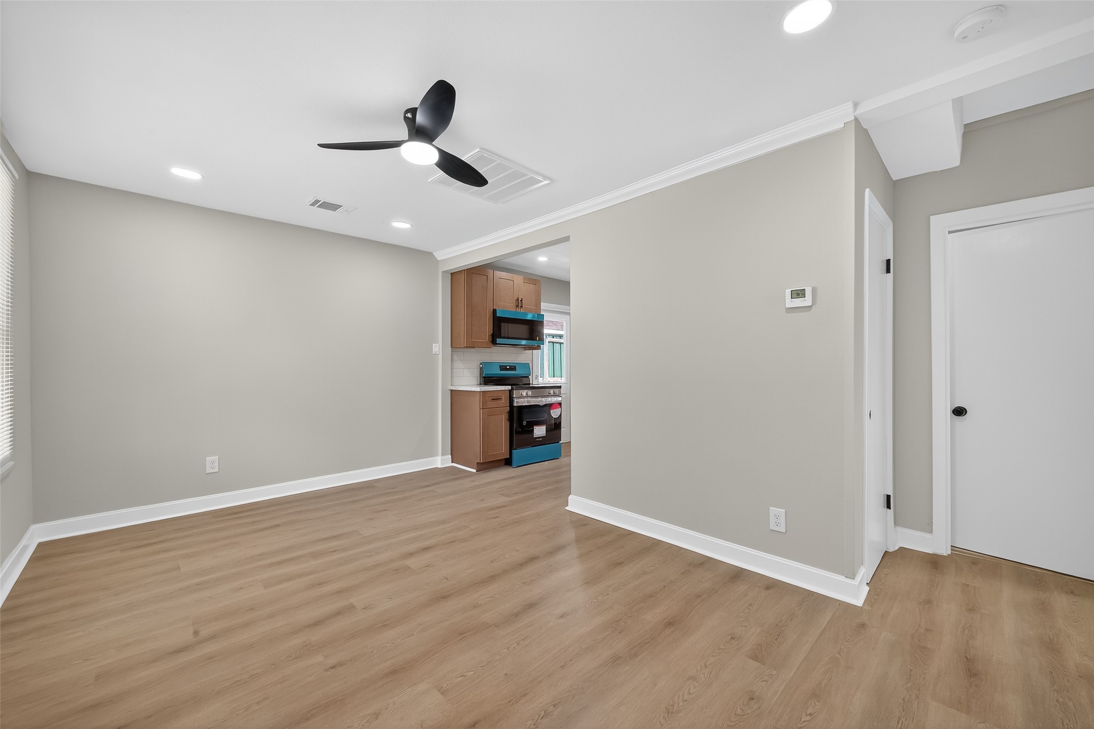 889 Chas Lane Houston, TX 77091 - Photo 5 of 32 a view of an empty room with wooden floor and a ceiling fan