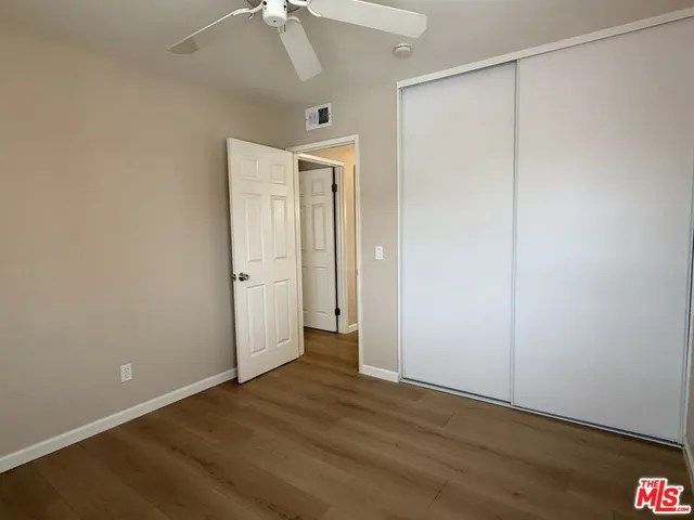 an empty room with wooden floor and a ceiling fan