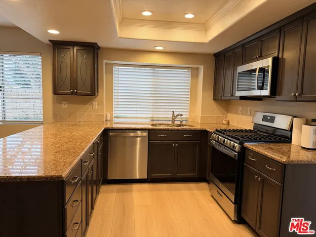 a kitchen with stainless steel appliances granite countertop a stove a sink and a microwave