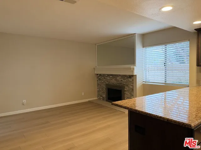 a view of an empty room with wooden floor and a fireplace