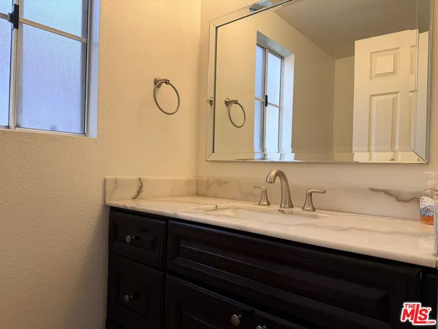 a bathroom with a granite countertop sink and a mirror