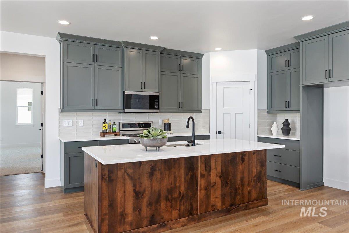 258 Maxine Lane, Unit HOMESITE 207 Kimberly, ID 83341 - Photo 2 of 19 Kitchen featuring gray cabinetry, backsplash, appliances with stainless steel finishes, an island with sink, and recessed lighting