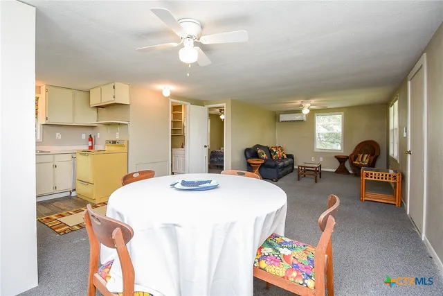 a very nice looking dining room with kitchen island a stove a sink a dining table and chairs with wooden floor