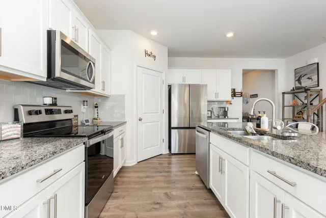 a kitchen with stainless steel appliances granite countertop a sink stove and refrigerator
