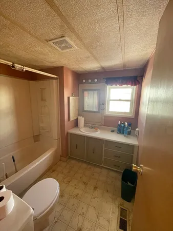a bathroom with a granite countertop sink mirror bathtub and toilet