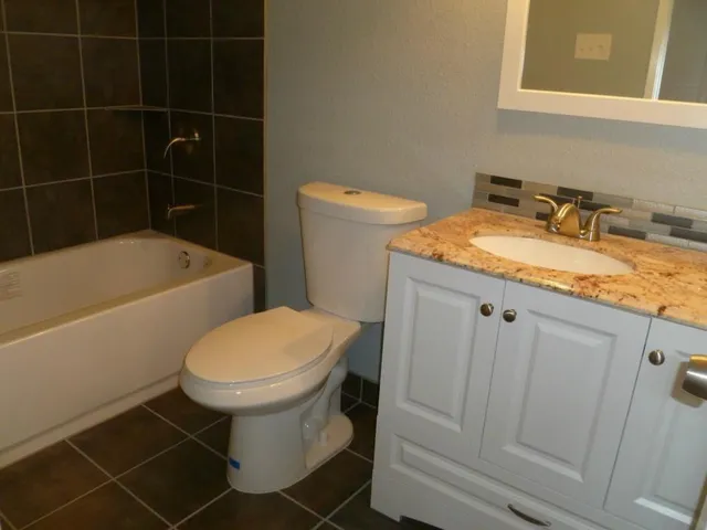 a bathroom with a granite countertop toilet a sink and bathtub