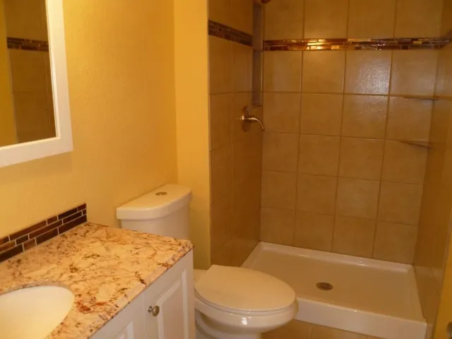 a bathroom with a granite countertop sink toilet and shower