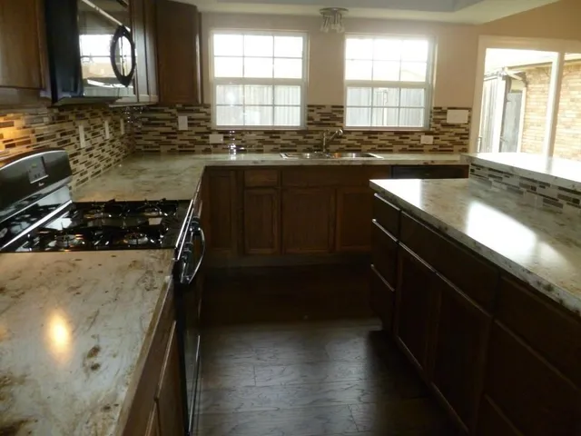 a kitchen with granite countertop a stove a sink and a window