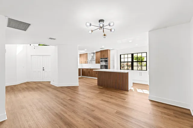 a view of kitchen and empty room with wooden floor