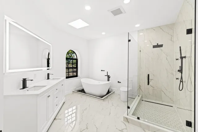 a bathroom with a white tub a sink and mirror