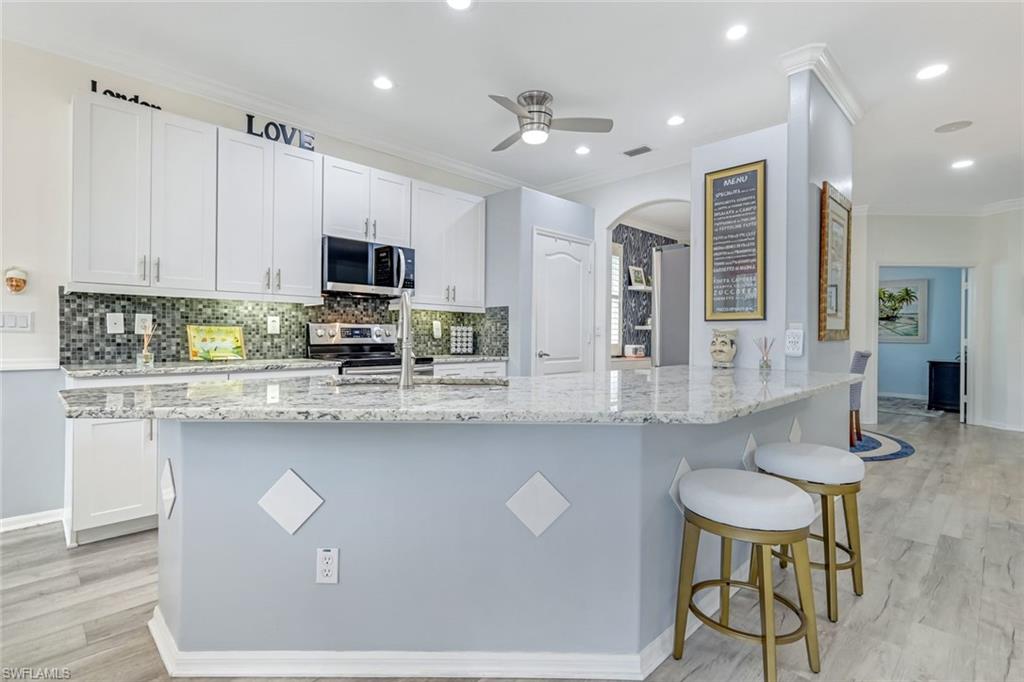 20050 Rookery Drive Estero, FL 33928 - Photo 12 of 45 a kitchen with stainless steel appliances granite countertop a stove a sink a microwave a dining table and chairs