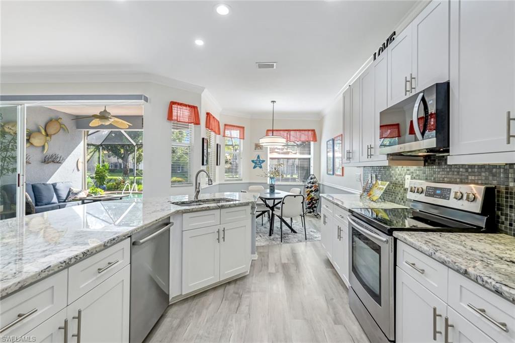 20050 Rookery Drive Estero, FL 33928 - Photo 13 of 45 a kitchen with stainless steel appliances granite countertop a lot of counter space and wooden floors
