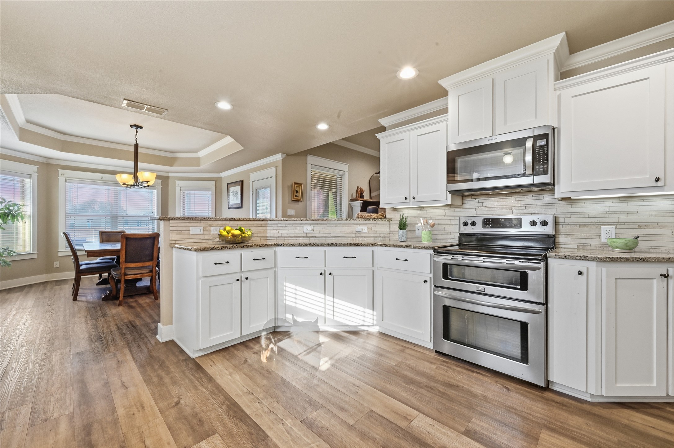 4467 West Amity Road Salado, TX 76571 - Photo 14 of 40 The kitchen features white cabinetry, stainless steel appliances, and a tiled backsplash, with hardwood style flooring throughout