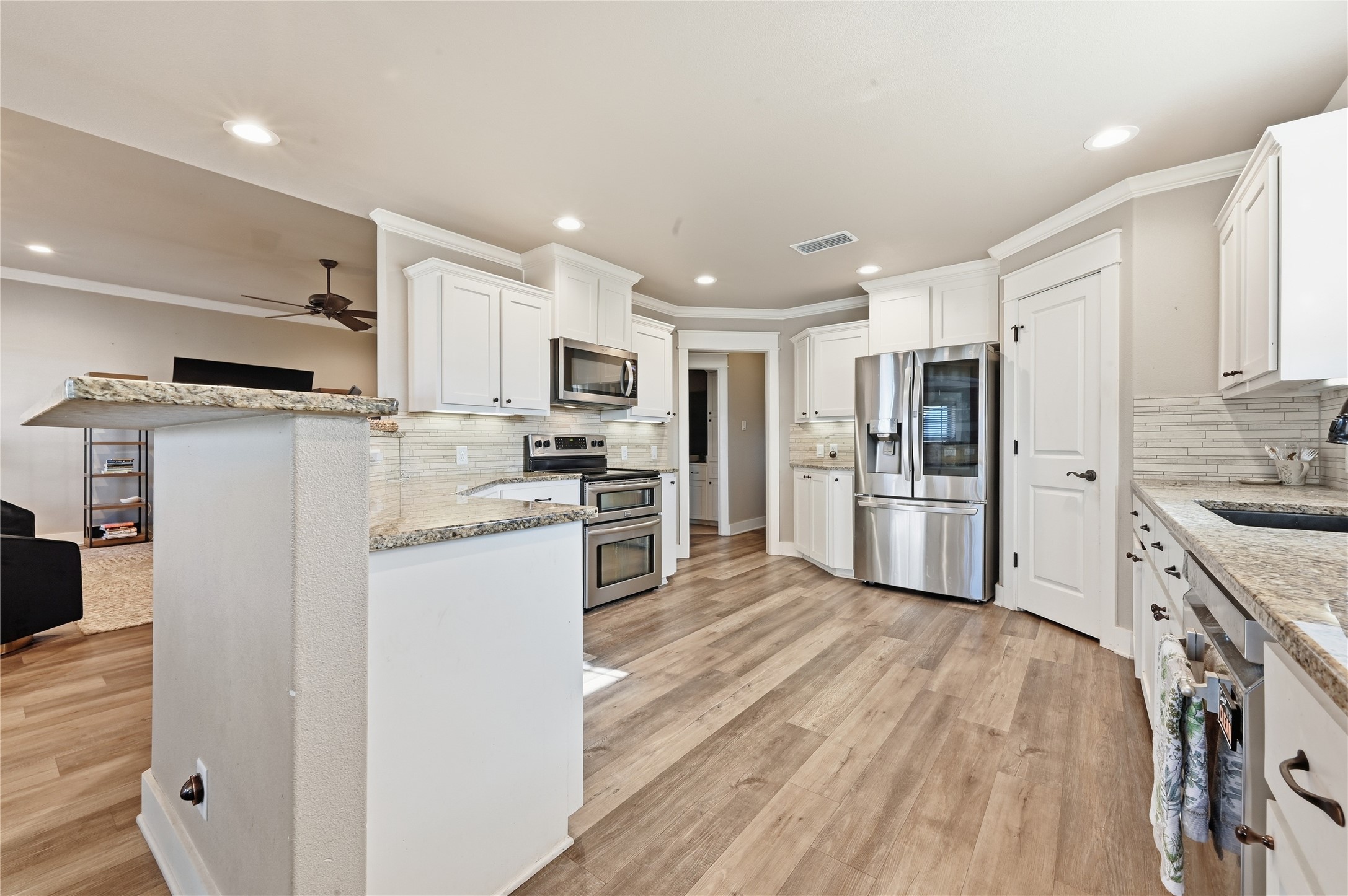 4467 West Amity Road Salado, TX 76571 - Photo 16 of 40 The kitchen features white cabinetry, granite countertops, stainless steel appliances, and wood-look flooring