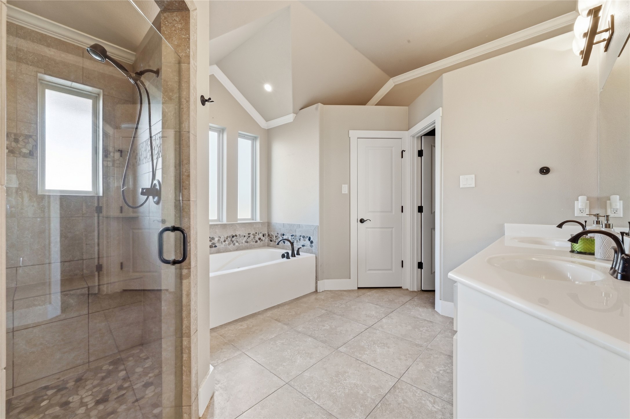 4467 West Amity Road Salado, TX 76571 - Photo 19 of 40 The bathroom features a glass-enclosed shower with a window, a soaking tub with decorative tile surround, and a dual vanity with undermount sinks and dark bronze fixtures