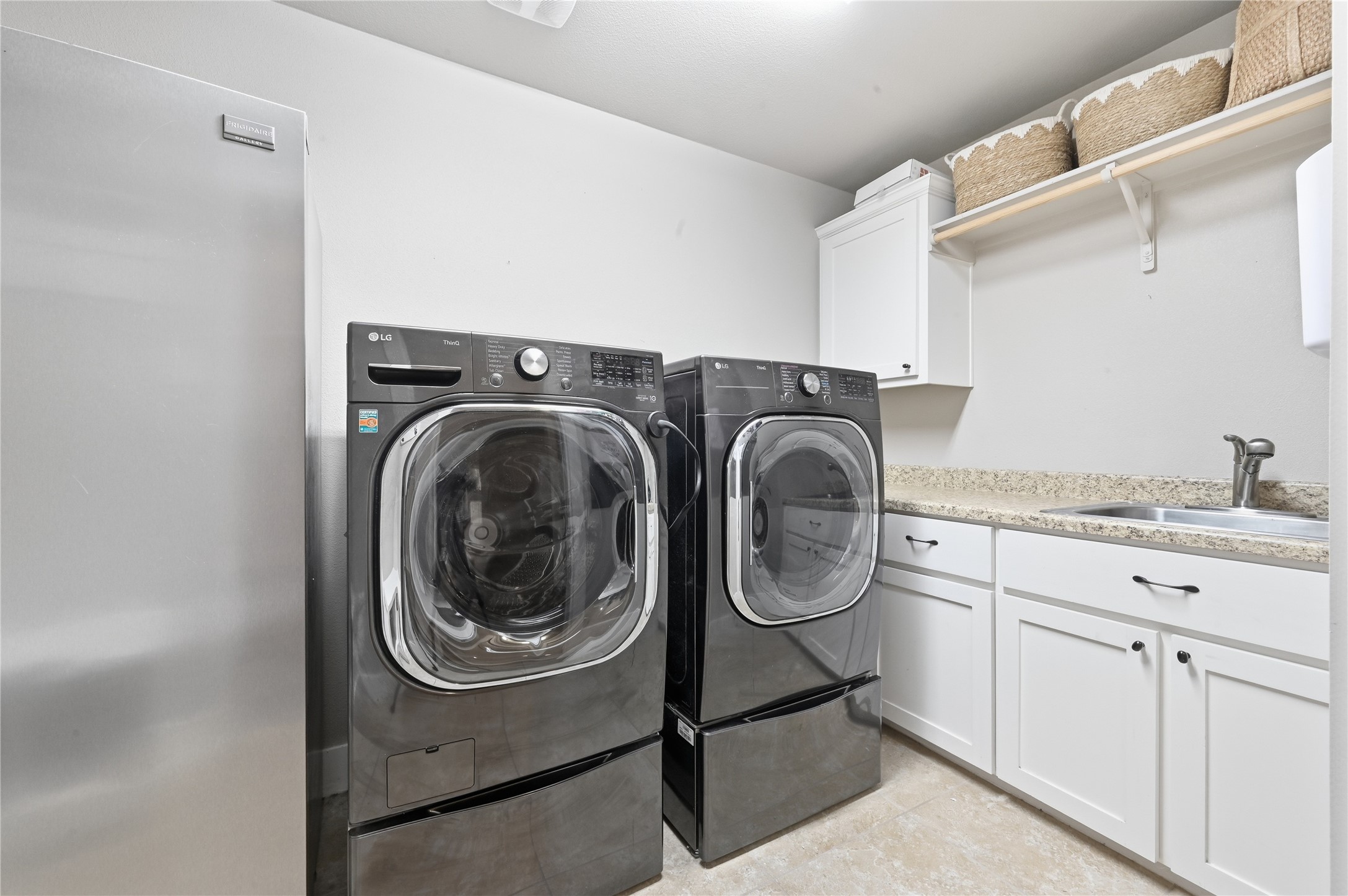 4467 West Amity Road Salado, TX 76571 - Photo 28 of 40 This utility room features light-colored walls, a stainless steel refrigerator, and a dark-toned washer and dryer set on pedestals