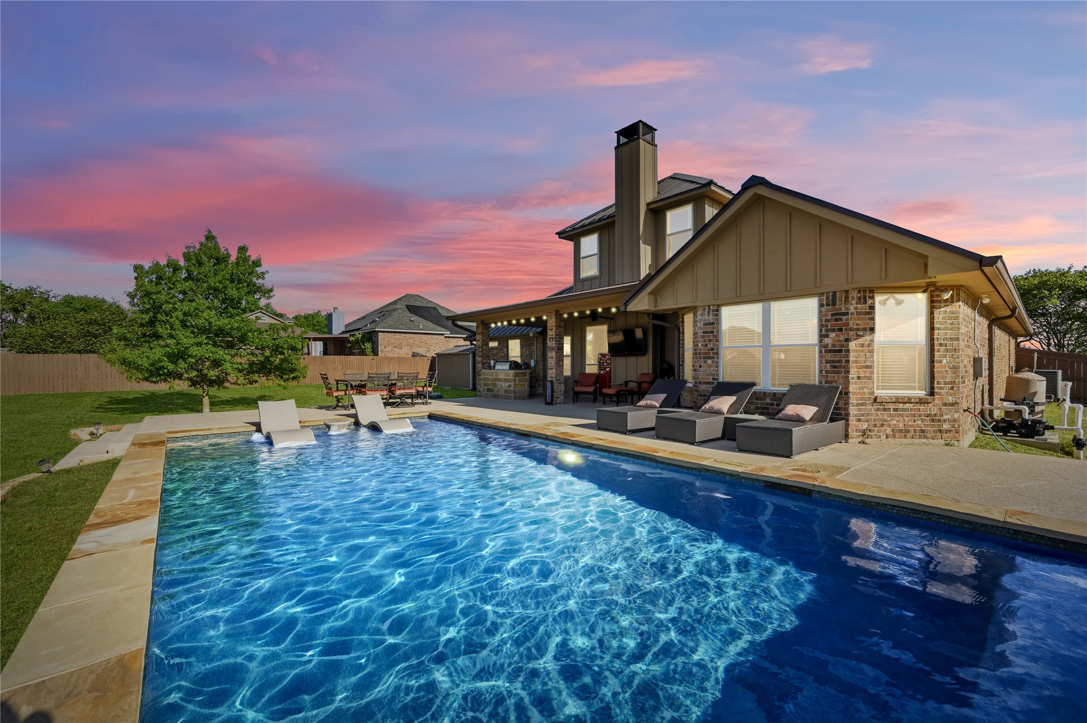 4467 West Amity Road Salado, TX 76571 - Photo 3 of 40 The property features a large swimming pool with an integrated tanning ledge, a spacious patio area with lounge chairs, and an outdoor kitchen under a covered patio