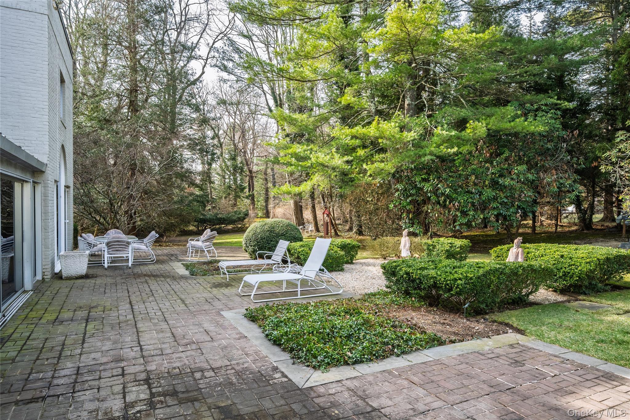 120 Bacon Road Old Westbury, NY 11568 - Photo 22 of 29 a view of a chair and tables in the patio along with trees