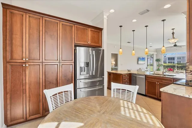 a kitchen with stainless steel appliances granite countertop a refrigerator a oven and white cabinets with wooden floors