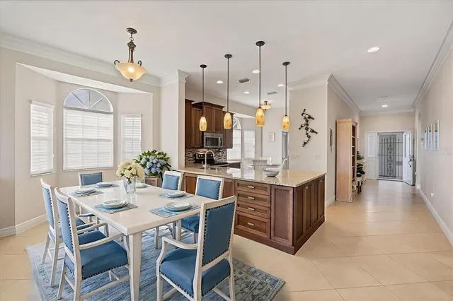 a kitchen island with stainless steel appliances a dining table chairs and a chandelier
