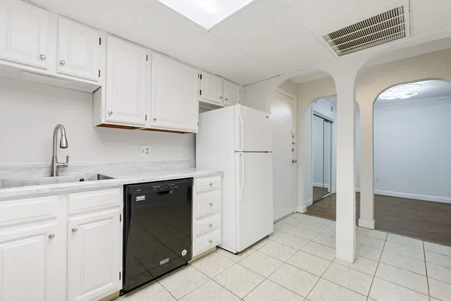 a kitchen with white cabinets and refrigerator