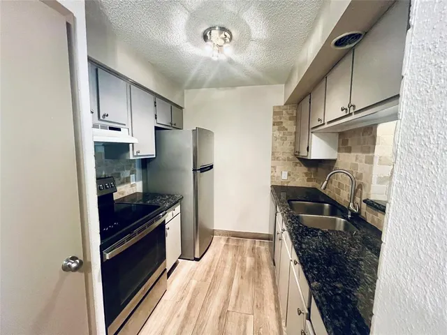 a kitchen with granite countertop a refrigerator stove and sink